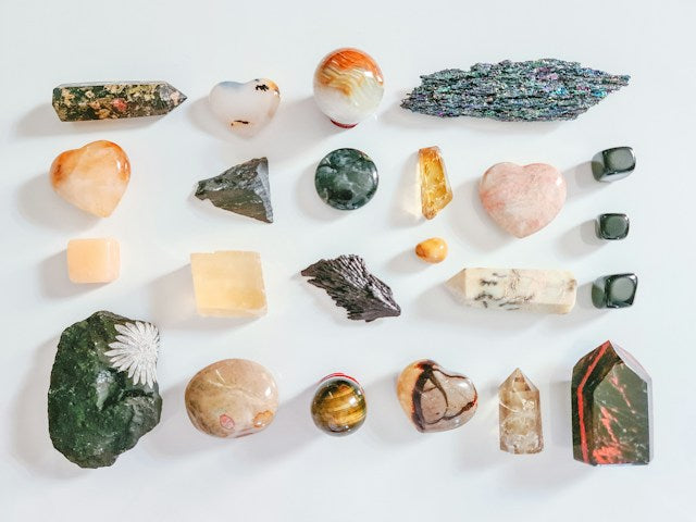 Colorful tumbled gemstones arranged around a natural clear crystal point